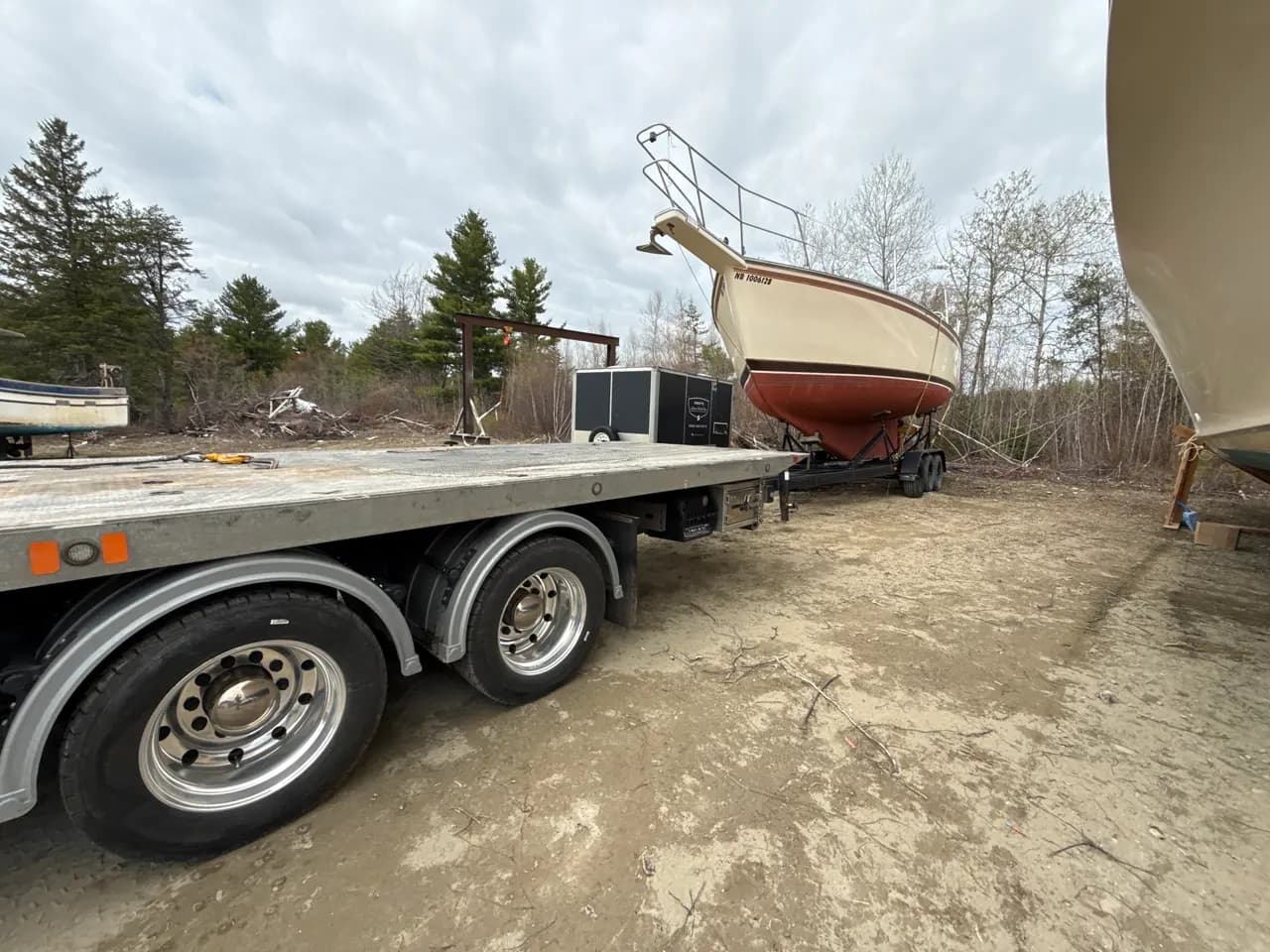 Dynamic Towing flat deck with a sailboat on a trailer at a New Brunswick lot