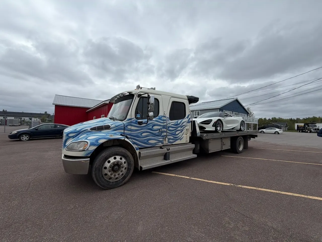 Dynamic Towing flat-deck rollback hauling a white exotic sports car