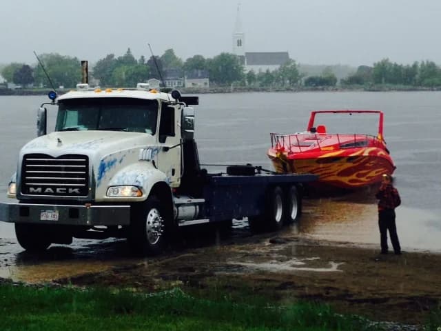 Plateforme Mack de Dynamic Towing récupérant un hors-bord à décoration de flammes à une rampe de mise à l'eau au Nouveau-Brunswick