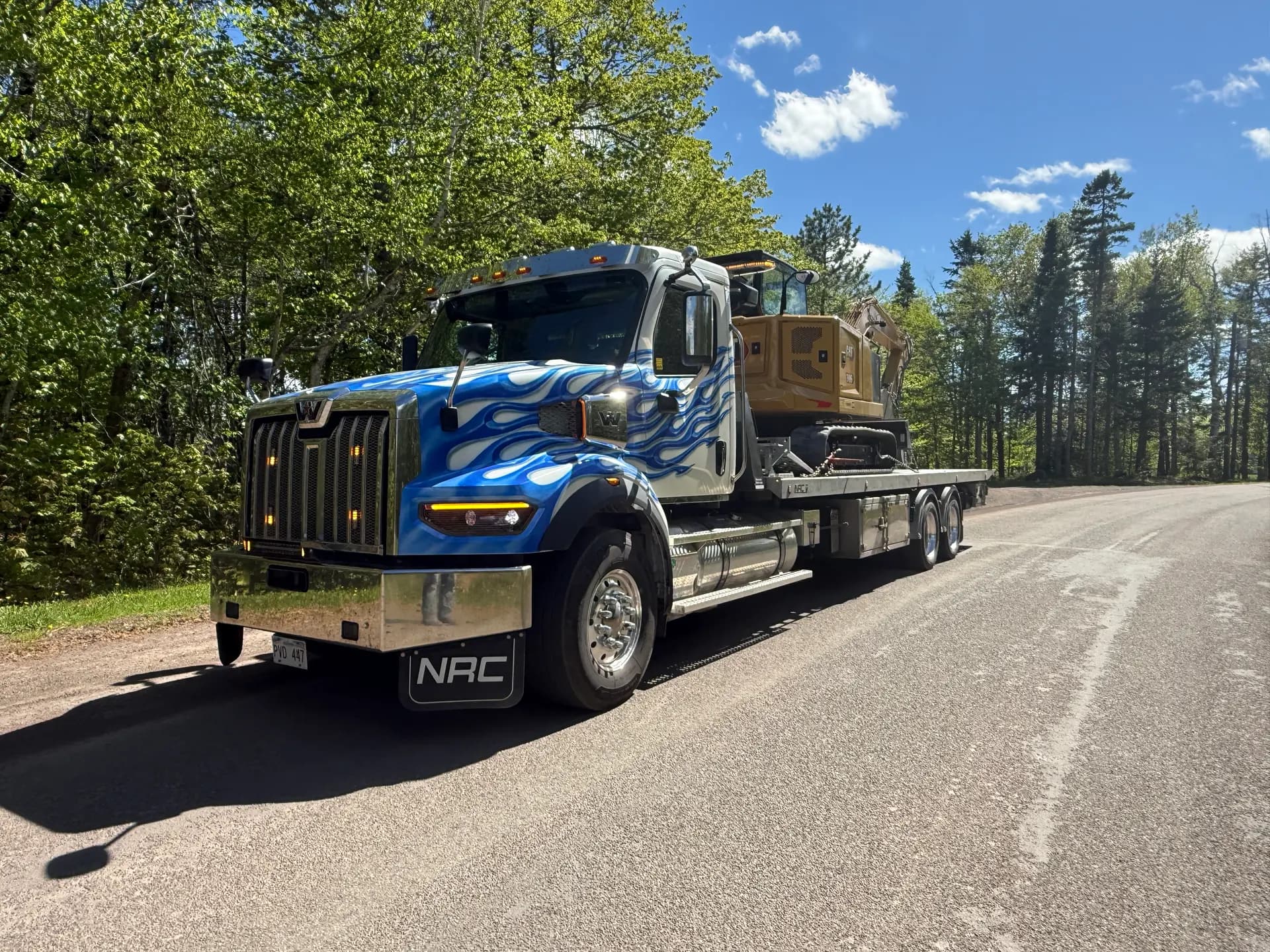 Dynamic Towing flat deck hauling an excavator on a rural New Brunswick road