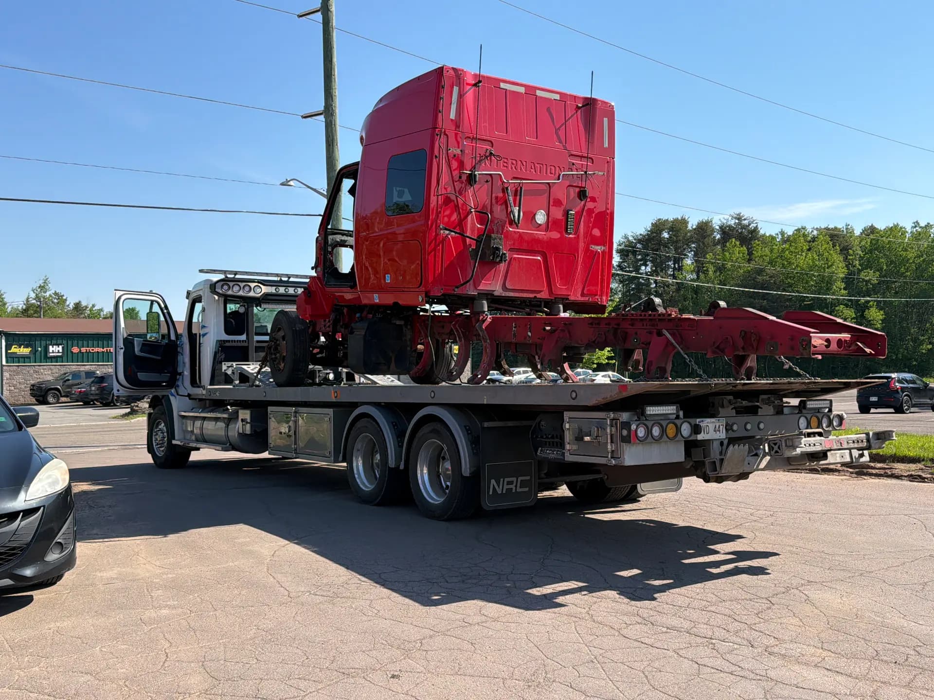Dynamic Towing flat deck hauling a damaged red International semi-truck cab