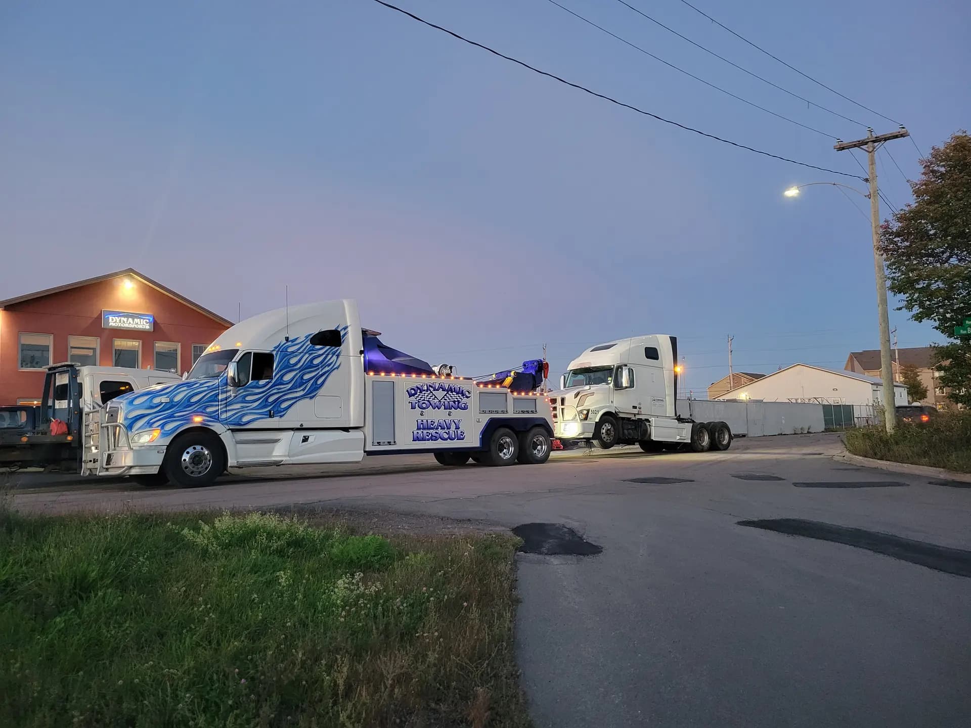 Dynamic Towing heavy wrecker towing a semi tractor at dusk
